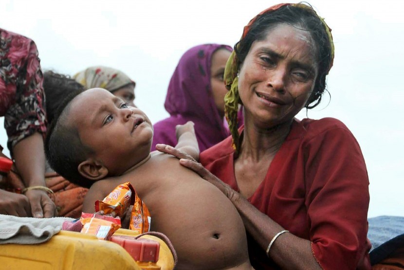 Seorang wanita muslim Rohingya Myanmar berada dalam sebuah perahu bersama bayinya dalam pelariannya ke Bangladesh untuk menghindari kekerasan antara umat Buddha lokal dan Muslim Rohingya. Muslim Rohingya ini dicegat oleh otoritas perbatasan Bangladesh di T