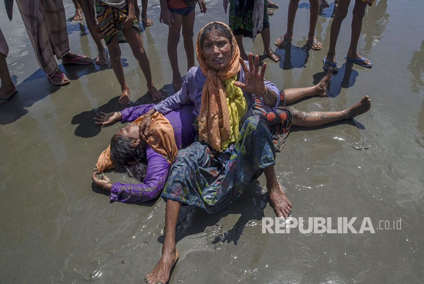 Seorang wanita Muslim Rohingya, yang menyeberang dari Myanmar ke Bangladesh, berteriak minta tolong karena kerabatnya tidak sadar setelah kapal yang mereka tumpangi dalam beberapa menit sebelum mencapai pantai di Shah Porir Dwip, Bangladesh, Kamis, (14/9).