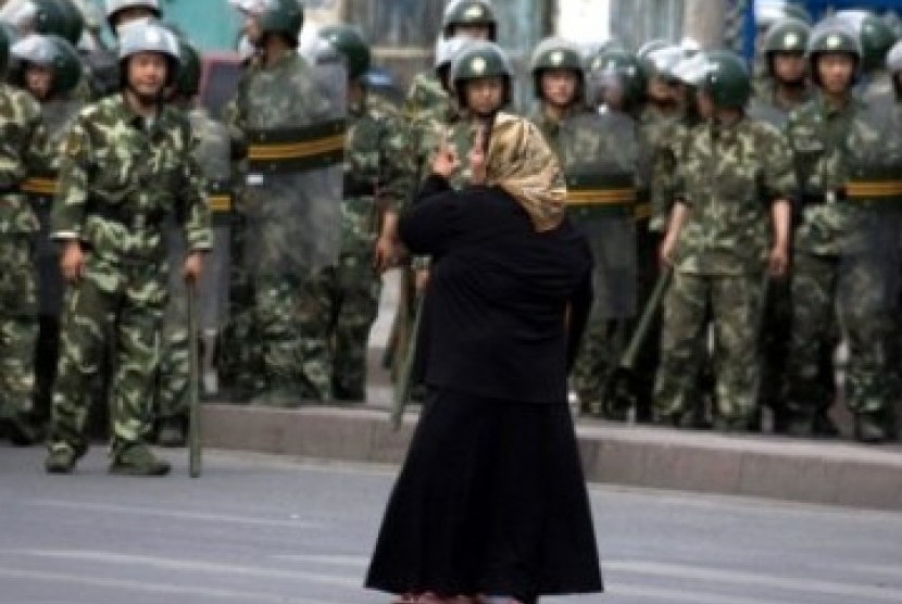 Seorang wanita Muslim Uighur  di Urumqi berhadapan dengan militer Cina