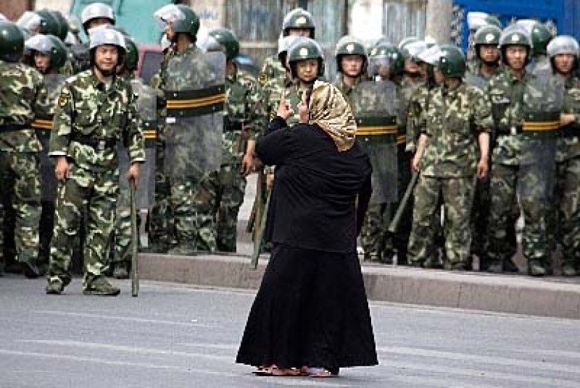 Seorang wanita Muslim Uighur di Urumqi, Xinjiang, berhadapan dengan militer Cina