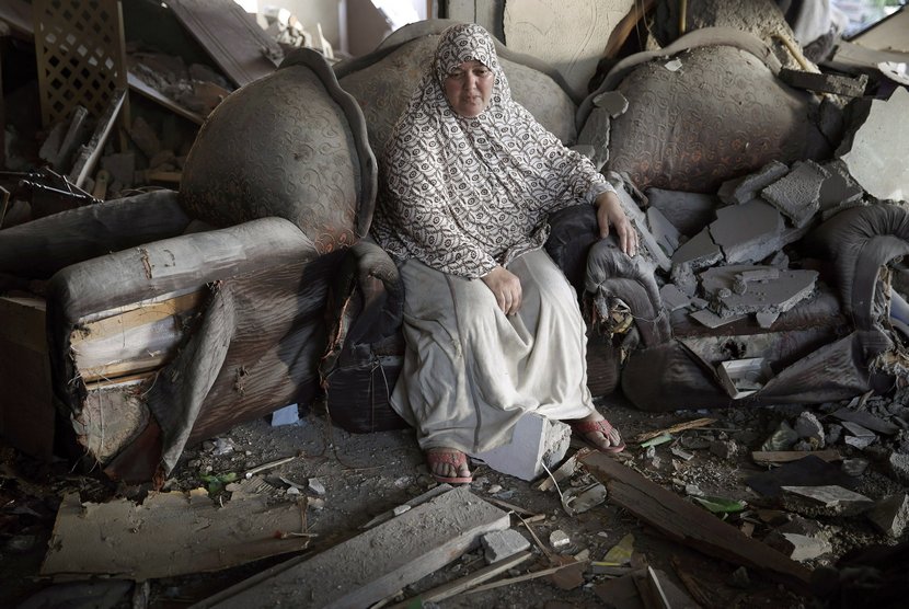  Seorang wanita Palestina duduk di dalam rumahnya yang hancur akibat serangan udara Israel, di Kota Gaza, Kamis (17/7).  (Reuters/Finbarr O'Reilly)