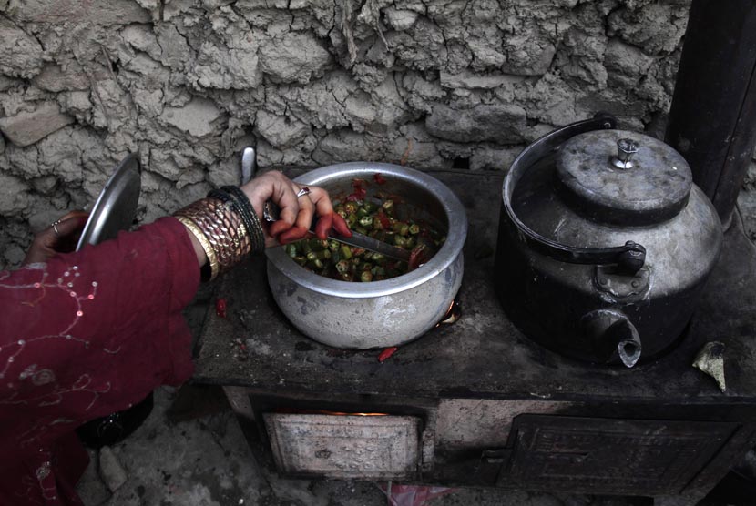 Seorang wanita pengungsi Afghanistan memasak makanan untuk berbuka puasa di Kabul, Afghanistan, Senin (22/7). (AP/Rahmat Gul)