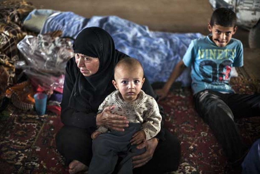 Seorang wanita pengungsi Suriah bersama cucunya di sebuah kamp pengungsi di desa Azaz dekat perbatasan dengan Turki,Ahad (30/9).