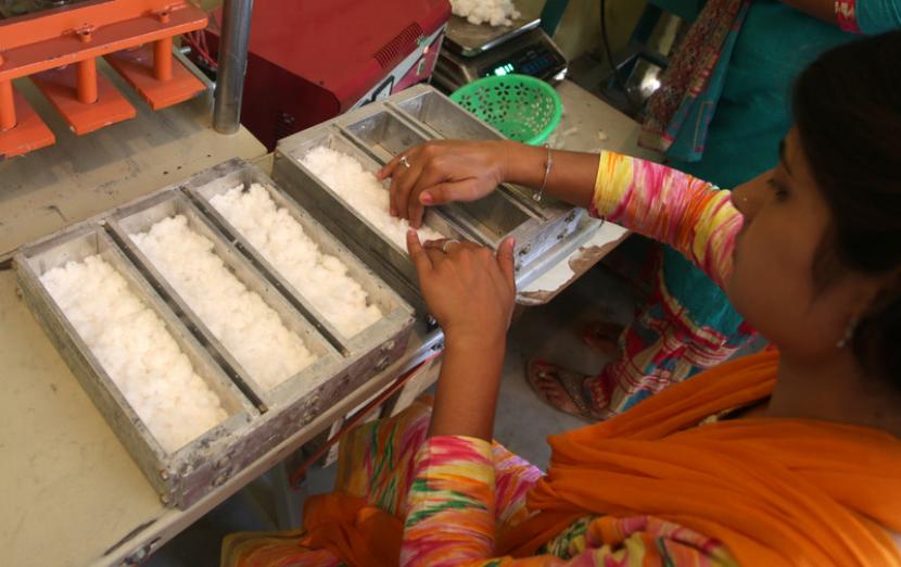 Seorang wanita sedang membuat pembalut wanita di pabrik di dekat Jammu dan Kashmir. 