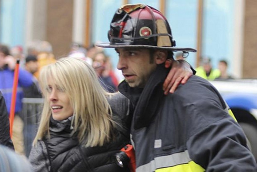 Seorang wanita terluka akibat ledakan di Maraton Boston 2013, Senin (15/4/2013)  tengah dievakuasi oleh seorang petugas PMK