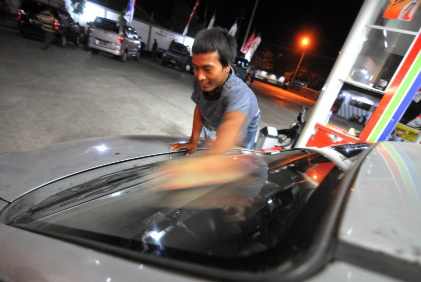 Seorang warg mengelap kaca mobil saat mengisi bahan bakar minyak (BBM) di SPBU.