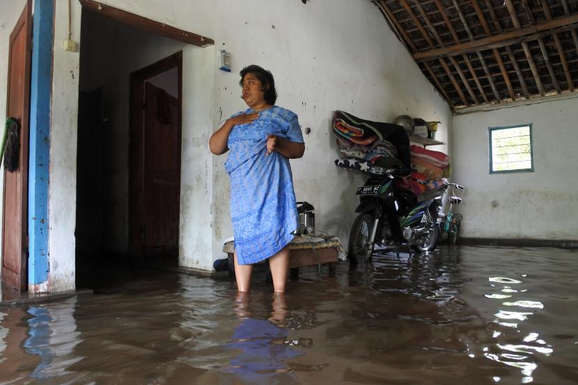 Seorang warga berada dalam rumah yang terendam banjir  (ilustrasi)