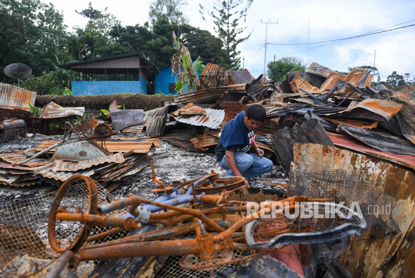 Seorang warga berada di puing rumahnya yang terbakar di kawasan Hom-hom, Kota Wamena, Kabupaten Jayawijaya, Papua, Sabtu (12/10/2019).