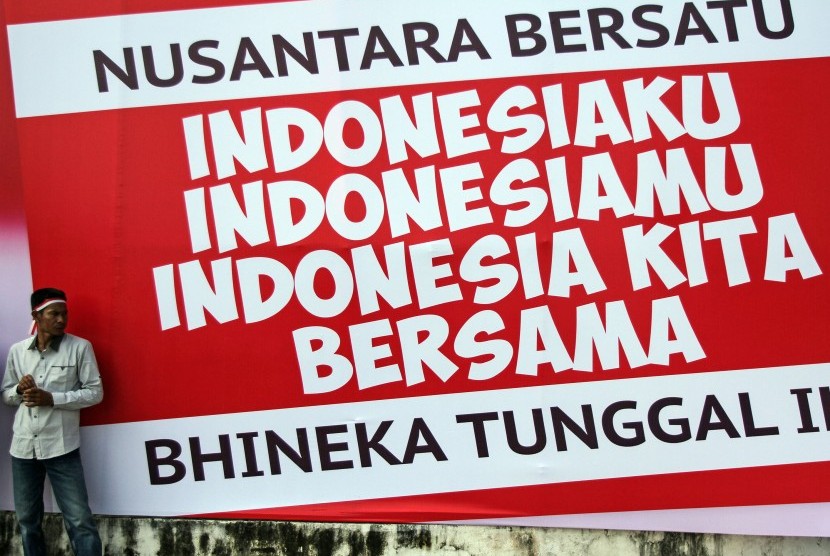 Seorang warga berdiri di depan spanduk Nusantara Bersatu. 
