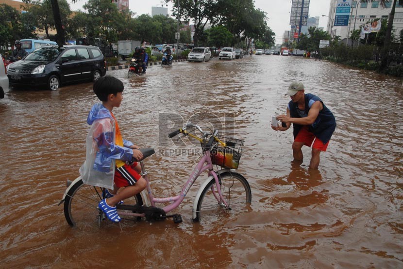  Seorang warga berfoto dengan anaknya di tengah banjir Jalan Boulevard Barat, Kelapa Gading, Jakarta Utara, Jumat (17/1).  (Republika/Rakhmawaty La'lang)