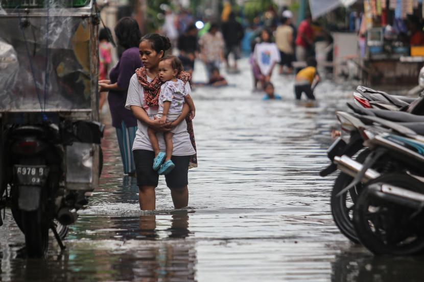 Seorang warga berjalan di tengah banjir di kawasan Cengkareng, Jakarta, Selasa (18/1/2022). Banjir tersebut terjadi karena buruknya drainase di kawasan itu serta tingginya instensitas hujan pada Selasa (18/1) siang. 
