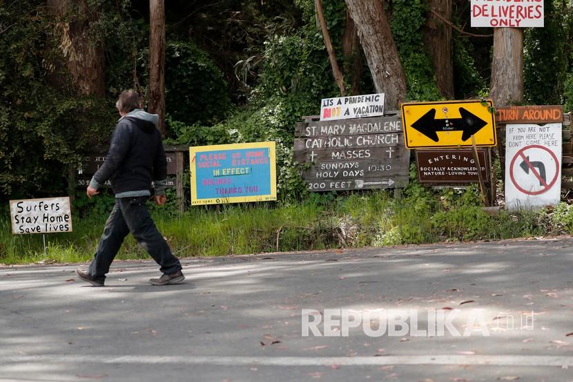 Amerika Serikat mencatat lonjakan kematian Covid-19 per hari 1.000 orang. Seorang warga berjalan melewati berbagai tanda-tanda tulisan di kota pantai terpencil, Bolinas, California, Amerika Serikat, Senin (20/4).  