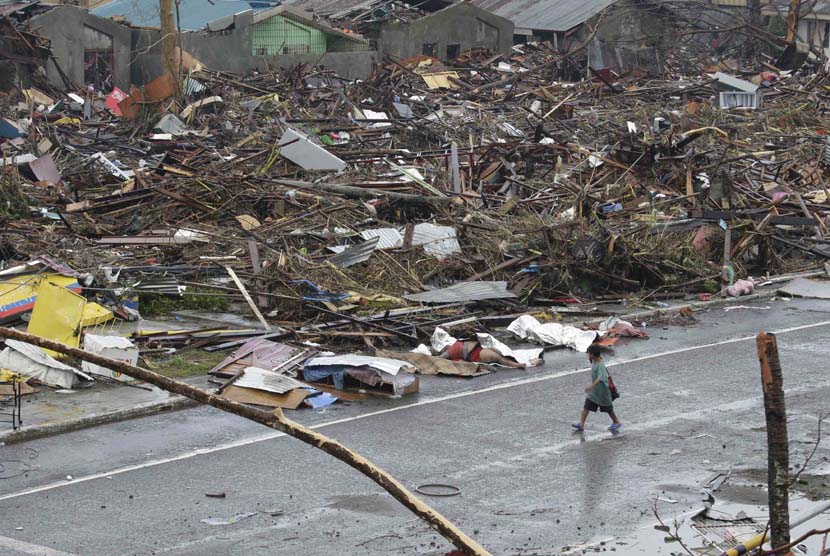  Seorang warga berjalan melewati pemukiman yang hancur akibat Topan Haiyan di kota Tacloban, Leyte provinsi Leyte, Filipina tengah, Ahad (10/11).  (AP/Bullit Marquez)