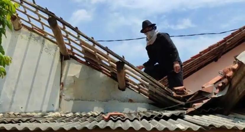 Seorang warga di Kecamatan Tukdana, Kabupaten Indramayu memperbaiki atap rumahnya yang beterbangan akibat angina puting beliung, Kamis (25/1/2024). Angin putting beliung menerjangtiga desa di Kecamatan Tukdana pada Rabu (24/1/2024) sore. 