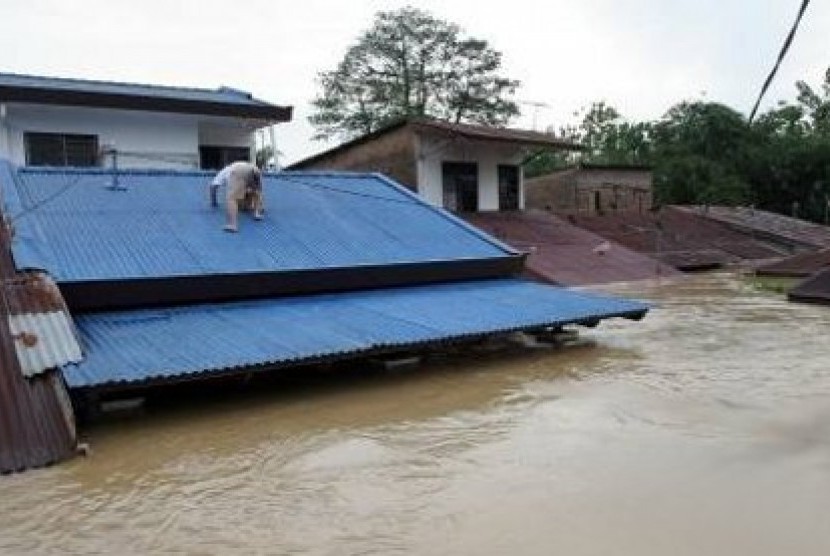 Seorang warga di Mandailing Natal, Sumatra Utara, naik ke atap rumahnya saat banjir melanda tahun lalu.