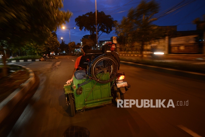 Seorang warga difabel menaikan kursi rodanya keatas motor seusai beraktifitas di Kawasan Basuki Rahmat, Jakarta Timur, Selasa (24/1) malam.