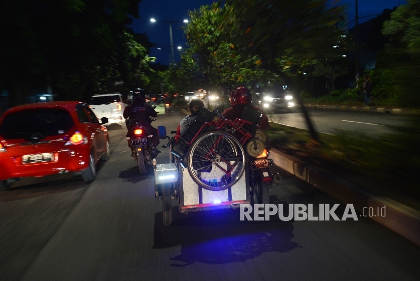 Seorang warga difabel menaikan kursi rodanya keatas motor seusai beraktifitas di Kawasan Basuki Rahmat, Jakarta Timur, Selasa (24/1) malam.