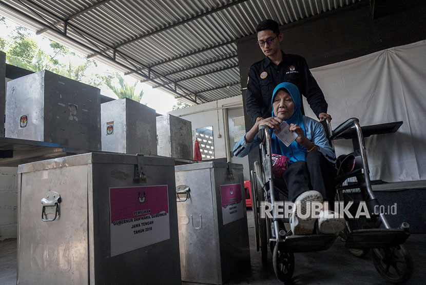 Seorang warga difabel mendapat bantuan saat memasukkan surat suara ke dalam kotak suara, saat simulasi pencoblosan Pilkada Serentak 2018, di Purwokerto, Banyumas, Jawa Tengah, Kamis (3/5).