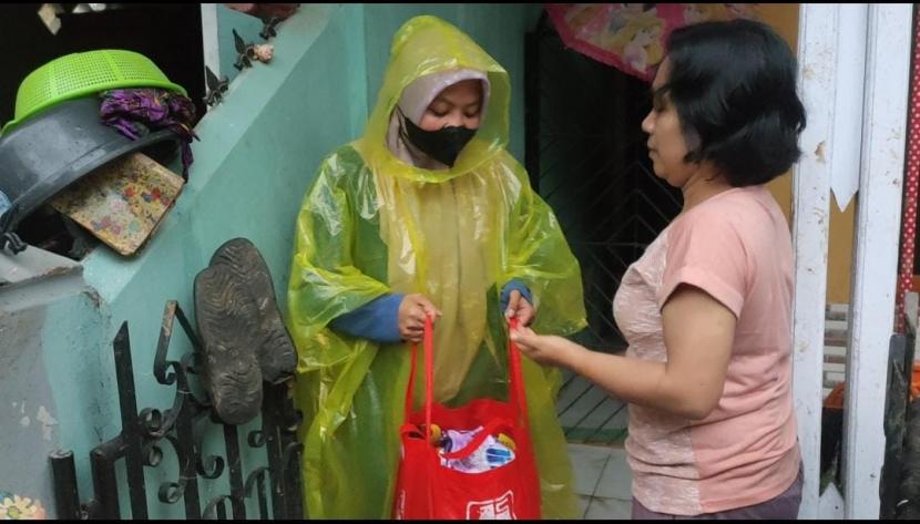 Seorang warga Dila Novianti (26) THL Pemkot Sukabumi ikut membantu warga terdampak banjir di Kelurahan Jayaraksa, Kecamatan Baros, Kota Sukabumi, Ahad (20/2/2022).i