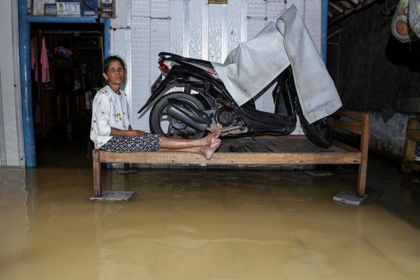 Seorang warga duduk di halaman rumahnya yang terendam banjir di Pakuhaji, Kabupaten Tangerang, Banten
