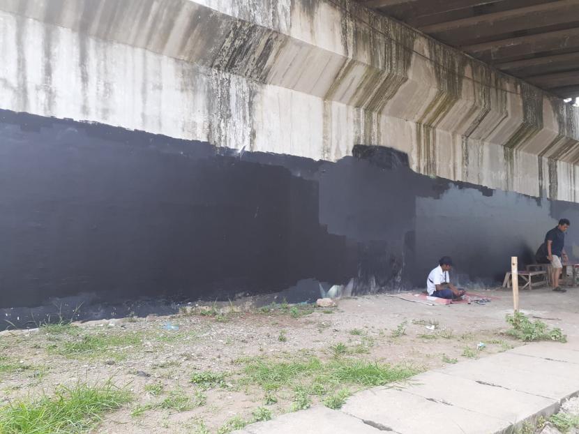 Seorang warga duduk di tembok, yang sebelumnya ada mural bergambar Presiden Jokowi bertuliskan 404: Not Found di bawah jembatan layang di Jalan Pembangunan 1, Kelurahan Batu Jaya, Kecamatan Batu Ceper, Kota Tangerang, Provinsi Banten, Ahad (15/8). 