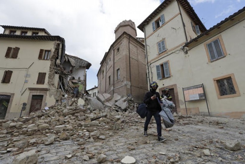 Seorang warga Italia melintas di depan menara lonceng yang runtuh gereja Santa Maria in Via di Kota Camerino, Italia tengah setelah diguncang gempa 5,9 SR, Kamis, 27 Oktober 2016.