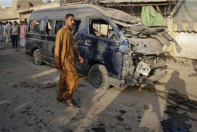 Seorang warga melewati bangkai mobil usai serangan bom mengguncang Peshawar, Pakistan, pada Rabu (19/9). 