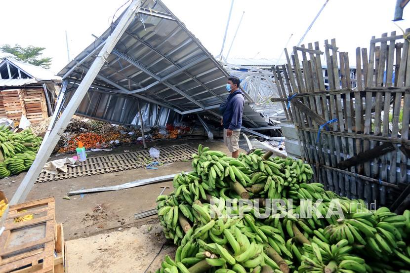 Seorang warga melihat atap bangunan kios yang roboh akibat terjangan angin kencang (ilustrasi)