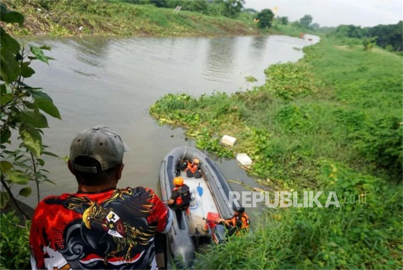 Seorang warga melihat petugas Tim SAR gabungan melakukan pencarian balita hanyut terseret arus di Kali Makmur kawasan perumahan Royal Residen Surabaya, Kamis (26/12/2024).