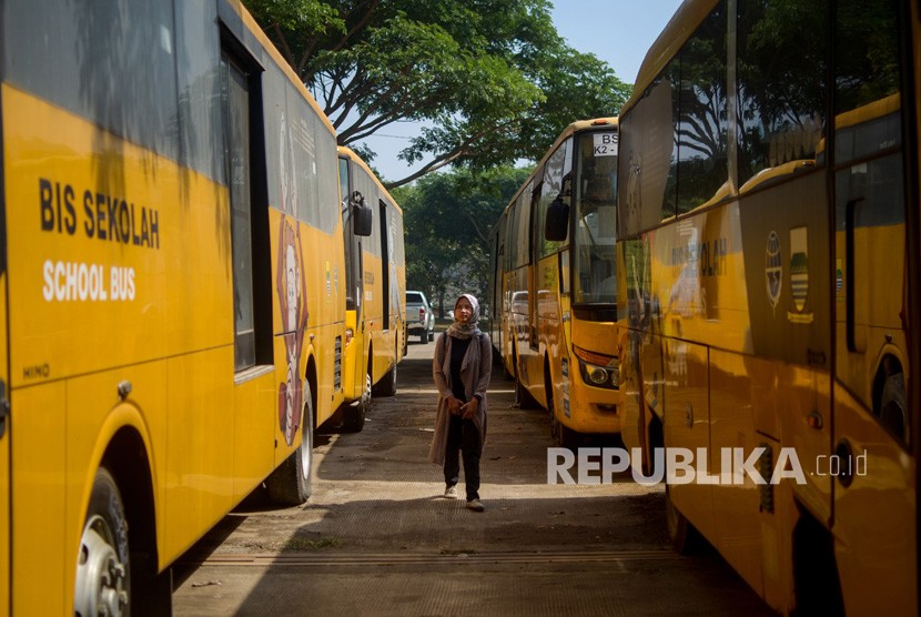 Seorang warga melintas di antara bus sekolah yang terparkir di Balai Pengujian Kendaraan Dinas Perhubungan, Gedebage, Bandung, Jawa Barat.