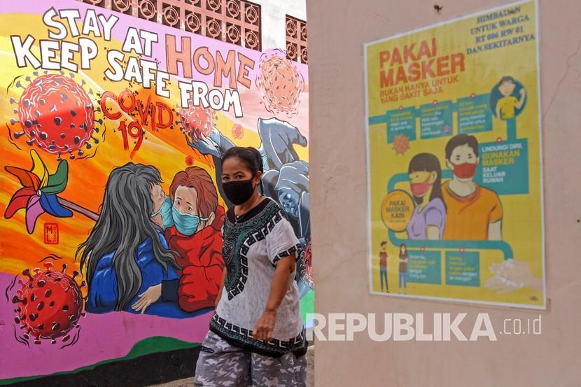 Seorang warga melintas di depan mural tentang COVID-19 di Pangkalan Jati Baru, Depok, Jawa Barat, Selasa (26/5/2020). Sejumlah aktivitas sosial dan ekonomi di Kota Depok boleh dibuka menyusul ditetapkannya PSBB Proporsional hingga awal Juli 2020.