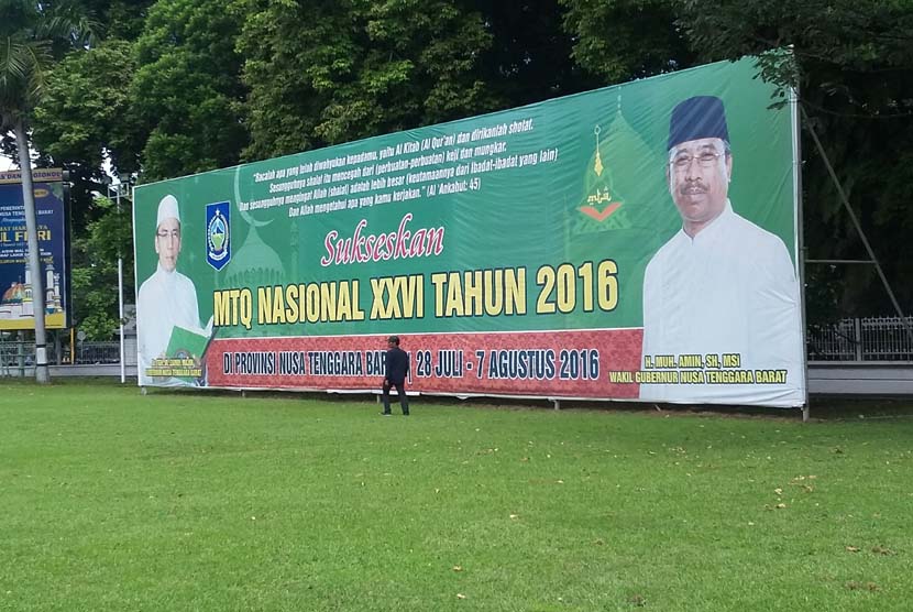 Seorang warga melintas di depan spanduk raksasa MTQ Nasional XXVI  di depan salah satu gedung instansi Pemerintah Provinsi NTB , di Mataram, Kamis (14/7/2016). MTQ Nasional XXVI akan digelar di Mataram, 28 Juli hingga 6 Agustus 2016.