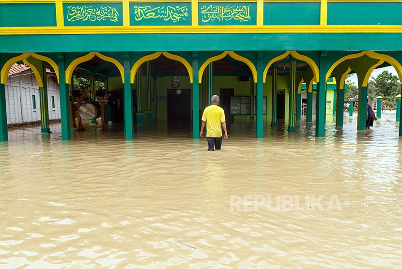 Seorang warga melintas di genangan air yang membanjiri sebuah masjid di Desa Kemiri, Grobogan, Jawa Tengah, Senin (10/10). Ribuan rumah di beberapa desa di Kabupaten Grobogan tergenang banjir akibat jebolnya tanggul Sungai Tuntang sepanjang 40 meter. 