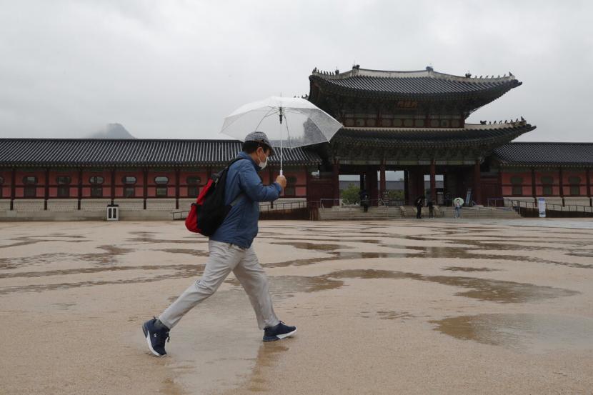 Seorang warga melintas di Gyeongbok Palace di Seoul, Korea Selatan, Rabu (22/7). Korea Selatan menghadapi banjir