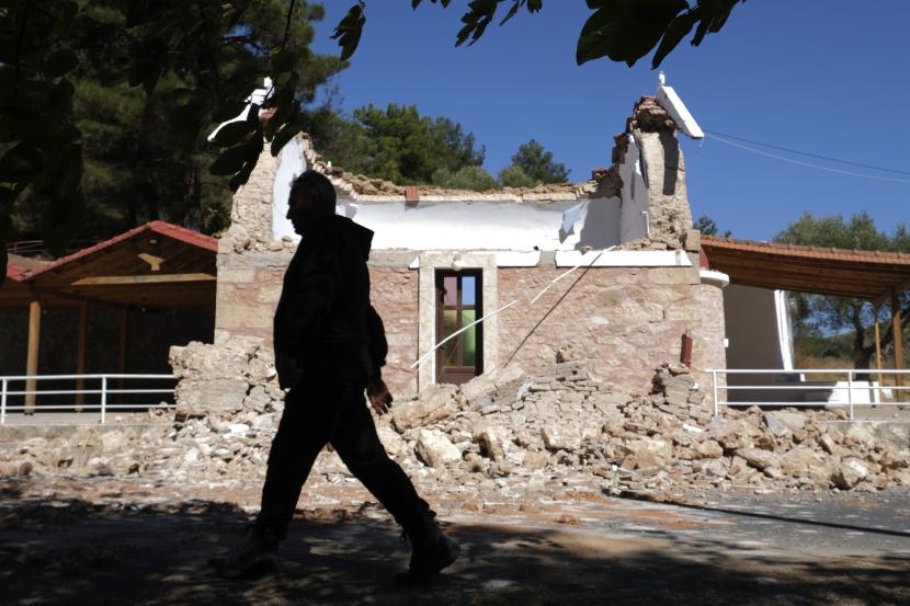Seorang warga melintas di sebelah kapel Ortodoks Yunani yang rusak setelah gempa kuat di desa Arcalochori di pulau selatan Kreta, Yunani, Senin, 27 September 2021.