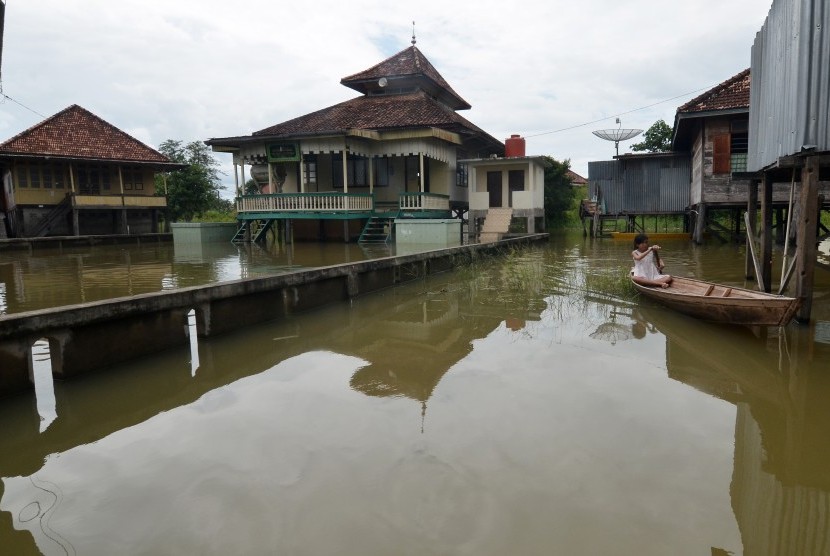 Seorang warga melintas menggunakan perahu di halaman rumahnya yang digenangi air luapan Sungai Batanghari, ilustrasi