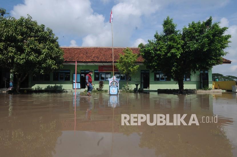 Seorang warga melintasi halaman sekolah yang terkena banjir di SD Negeri 1 Jetis, Juwiring, Klaten, Jawa Tengah, Jumat (4/3/2022). Hujan lebat pada kamis (3/3/2022) malam membuat sejumlah wilayah di kabupaten Klaten terkena banjir luapan sungai.