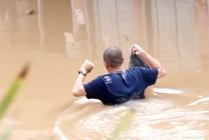 Seorang warga melintasi jalan yang sudah tertutup oleh banjir di Jakarta