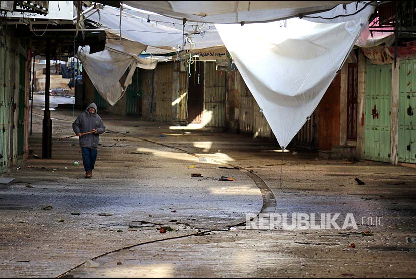 Seorang warga melintasi pertokoan di Hebron, Tepi Barat, Palestina.