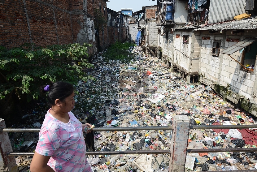 Seorang warga melintasi sungai yang dipenuhi sampah di Muara Baru, Jakarta utara, Selasa (19/5).