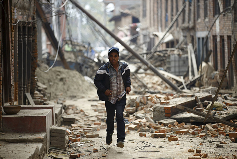  Seorang warga melitasi bangunan yang hancur akibat gempa bumi di Kathmandu, Nepal, Ahad (26/4). (Reuters/Navesh Chitrakar)