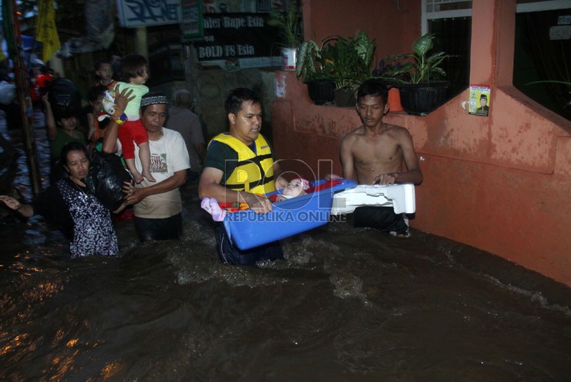   Seorang warga membawa anaknya yang masih balita ketika melintasi banjir yang merendam kawasan Kampung Pulo, Jakarta, Ahad (12/1).    (Republika/Yasin Habibi)