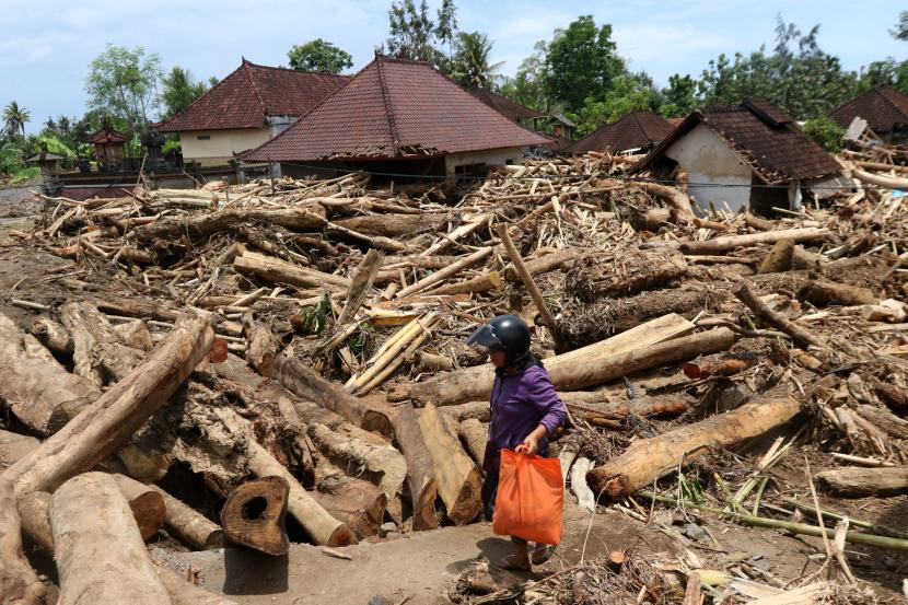 Seorang warga membawa barang yang masih bisa diselamatkan setelah rumahnya diterjang banjir bandang di Desa Tegal Cangkring, Jembrana, Bali, Kamis (20/10/2022). Badan Penanggulangan Bencana Daerah (BPBD) Jembrana mencatat banjir bandang pada Minggu (16/10) yang membawa material kayu dan lumpur itu mengakibatkan 156 rumah warga terendam, tujuh jembatan putus dan 1 orang meninggal dunia.