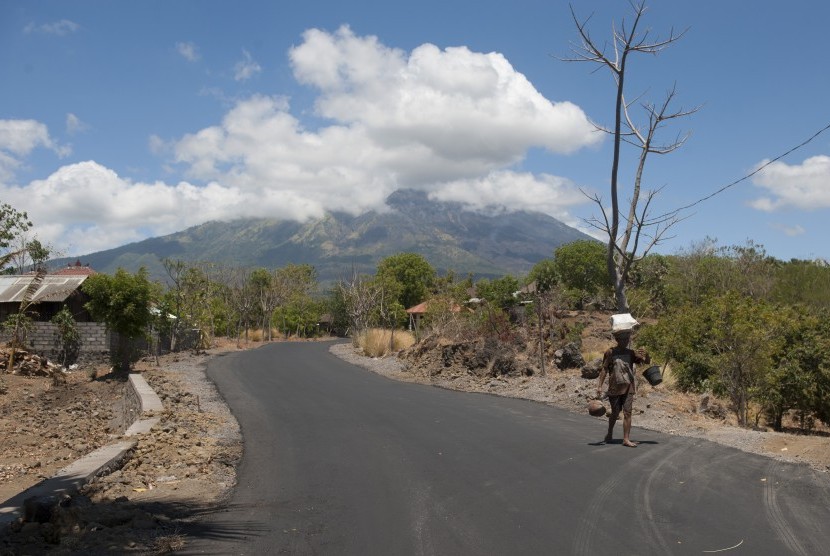 Seorang warga membawa hasil kebun di Desa Batu Dawa yang berjarak sekitar 10 kilometer dari Gunung Agung, Karangasem, Bali, Senin (25/9). 