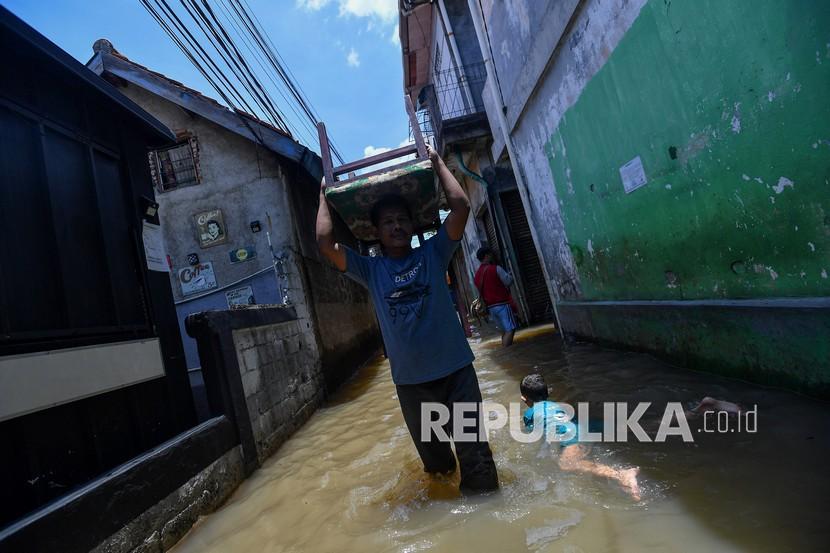 Seorang warga membawa kursi di atas kepalanya saat banjir melanda kawasan permukiman di Petogogan, Kebayoran Baru, Jakarta Selatan, Senin (5/10/2020). Banjir tersebut terjadi akibat meluapnya Kali Krukut.