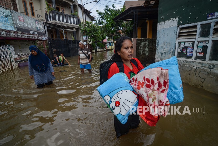 Seorang warga membawa perlengkapan tidur untuk mengungsi dari rumahnya yang terendam banjir di Kampung Bojong Asih, Dayeuhkolot, Kabupaten Bandung, Senin (12/11/2018).