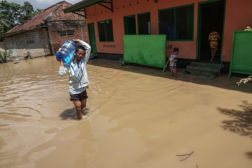 Seorang warga membawa persediaan air bersih melewati banjir yang melanda Desa Prembun, Tambak, Banyumas, Jateng, Jumat (18/11). 