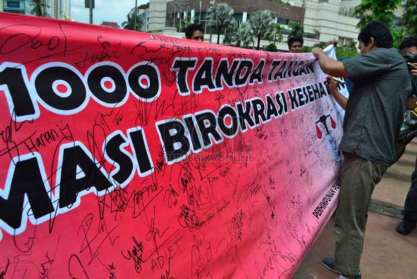  Seorang warga memberikan tanda tangannya disebuah spanduk saat aksi gerakan 1000 tanda tangan peduli reformasi birokrasi kesahatan di kawasan Bundaran HI, Jakarta, Ahad (3/2).   (Republika/Agung Supriyanto)