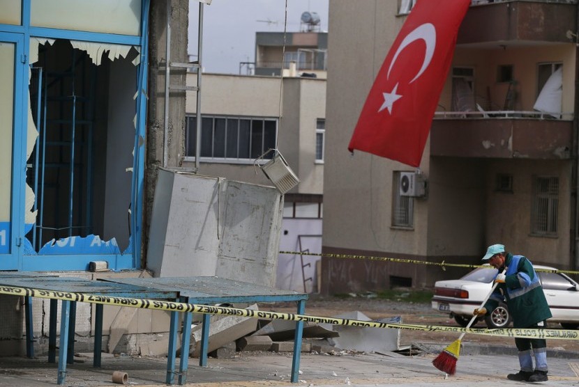 Seorang warga membersihkan pecahan kaca setelah serangan roket di Kota Kilis, Turki, Ahad (21/1).