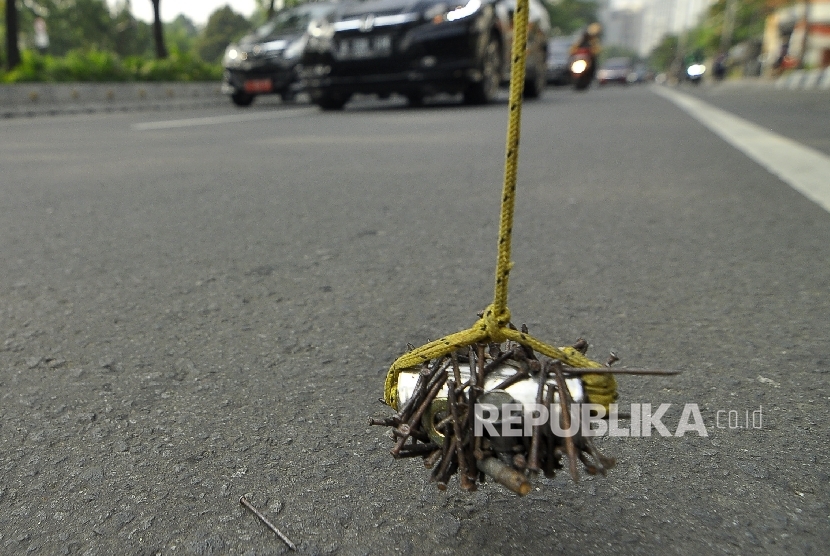  Seorang warga membersihkan ranjau paku menggunakan magnet (ilustrasi). Petugas Satuan Polisi Pamong Praja (Satpol PP) mengadakan operasi yang menjaring ranjau berupa paku hingga bekas potongan besi tajam di sejumlah titik di Jakarta Pusat.